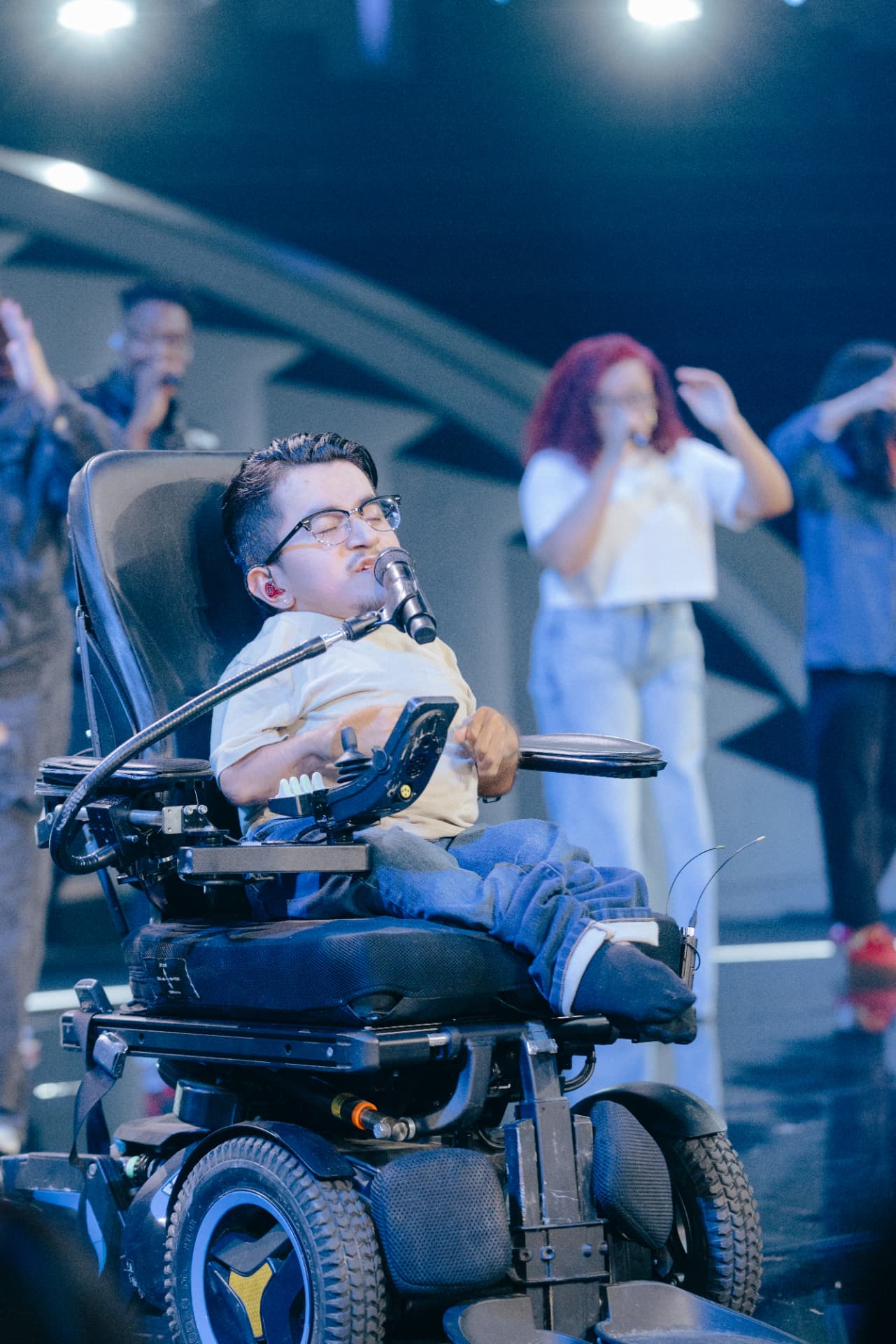 Isaac Immanuel on stage with singers, eyes closed mid-worship